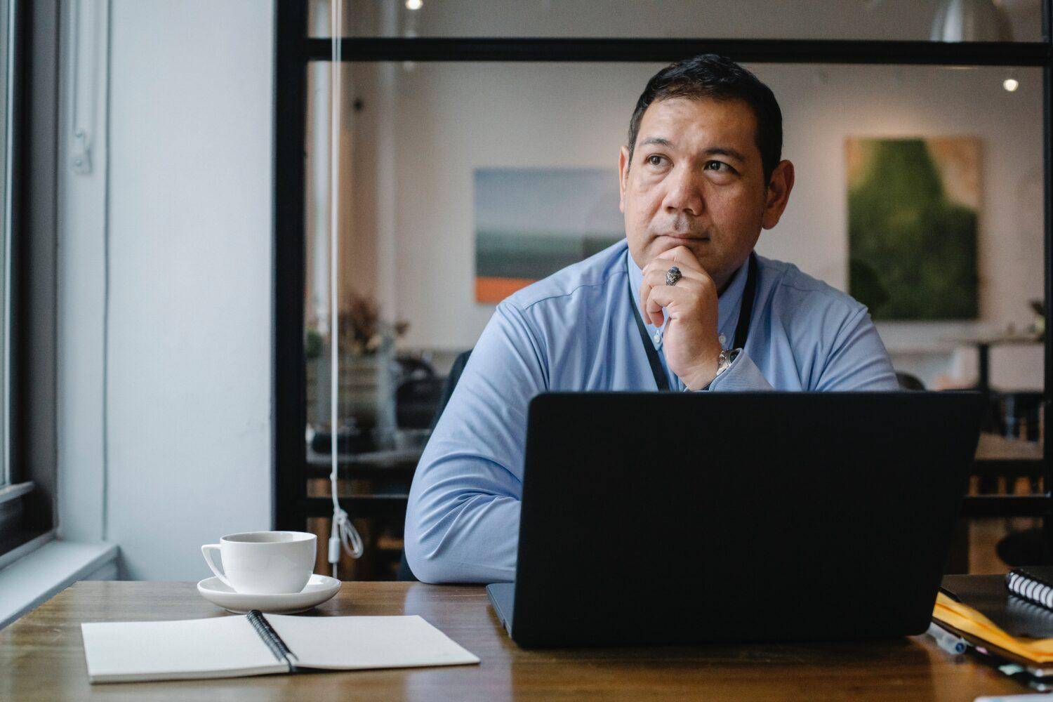 Thoughtful man seated at a desk with a laptop, representing a focused approach to mastering English skills through personalized guidance at English Class CDMX.