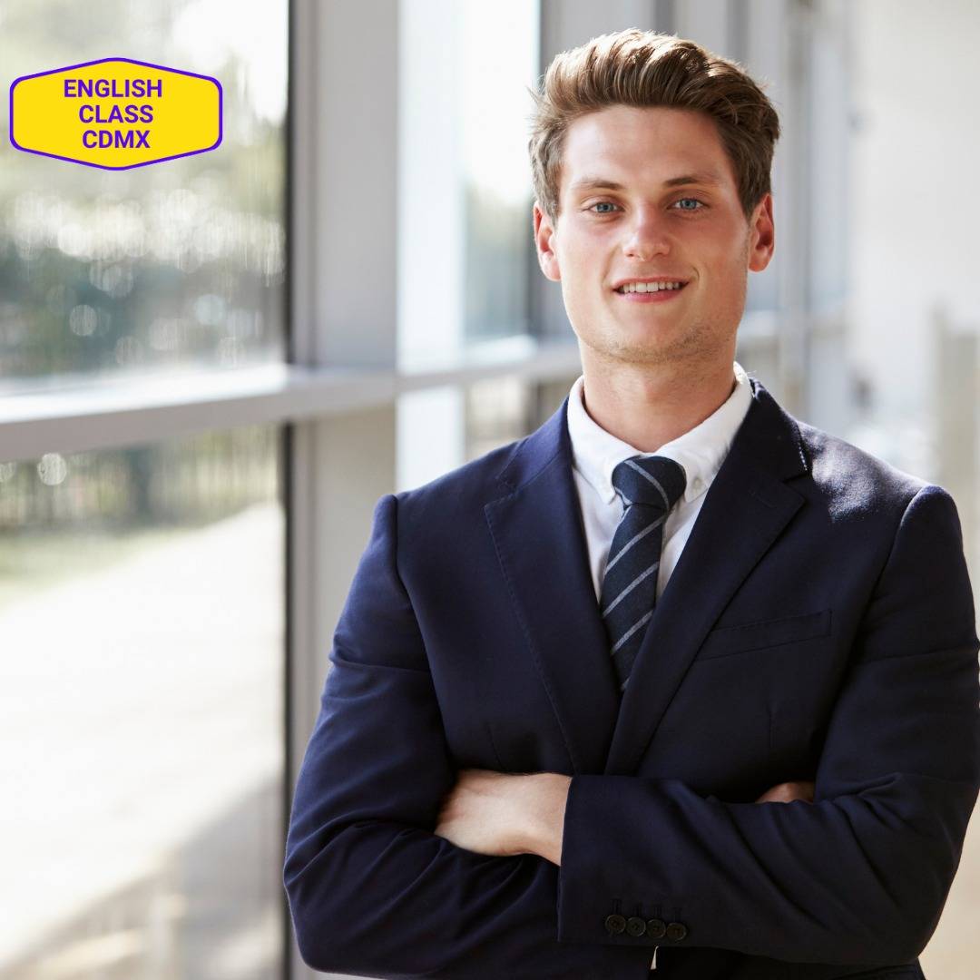 Confident young man in a business suit, smiling and standing with his arms crossed, symbolizing growth in interpersonal communication skills through professional English coaching at English Class CDMX.