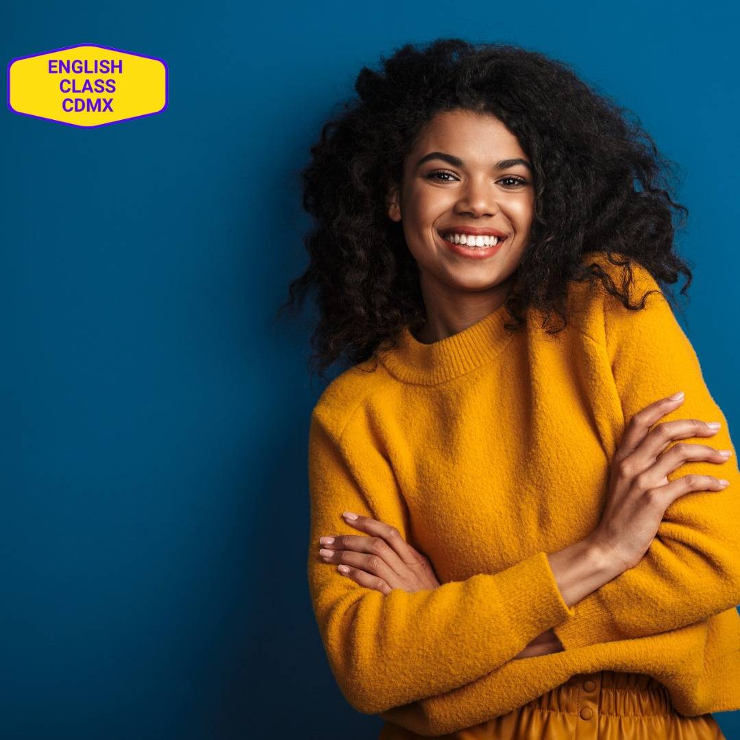 Smiling young woman in a vibrant yellow sweater, embodying confidence and positivity through mental attitude training offered by English Class CDMX.