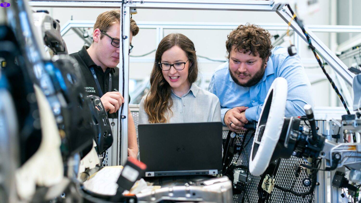 Three professionals collaborating on a technical project with a laptop, illustrating teamwork and advanced English skills for technical discussions and problem-solving