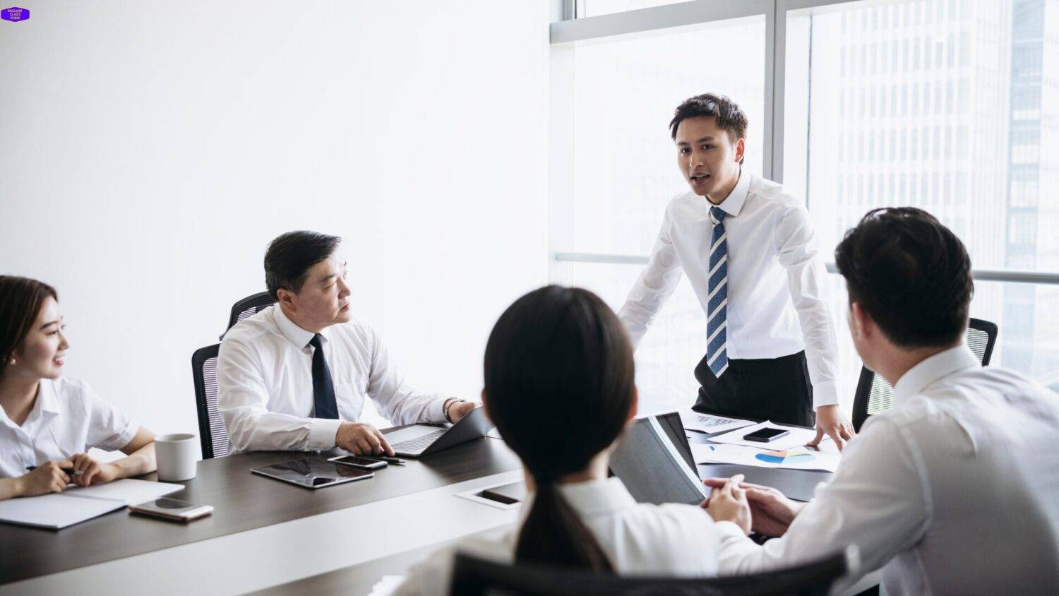 Group of professionals engaged in a discussion during a business meeting, part of the English speaking course focused on real-world communication skills.