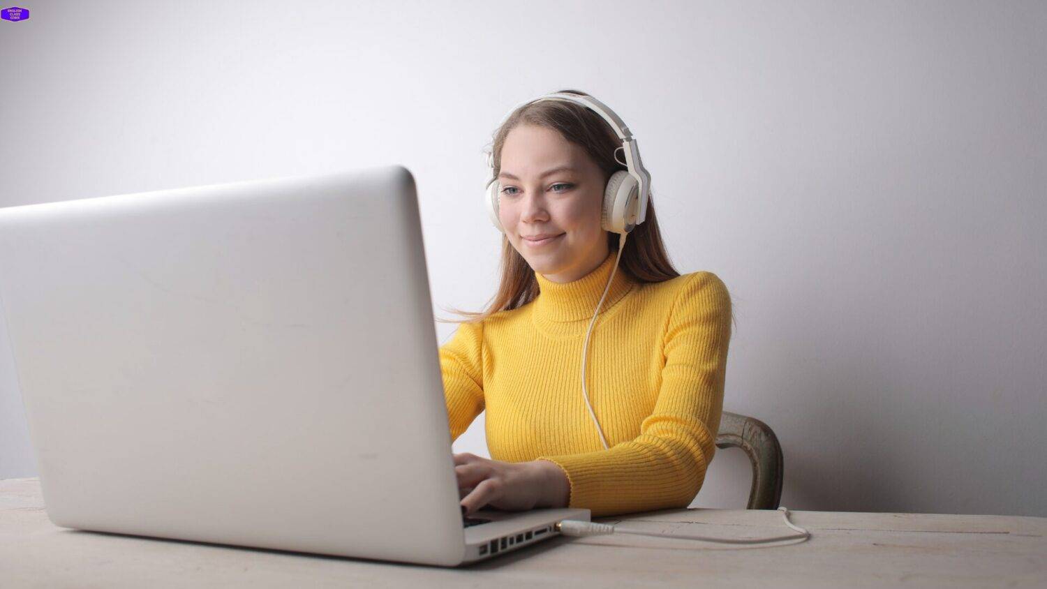 Student wearing headphones and learning English online with a laptop, focused and motivated to improve language skills.