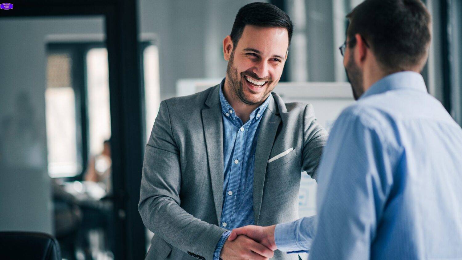 Two professionals shaking hands in a bright office, symbolizing growth and collaboration.